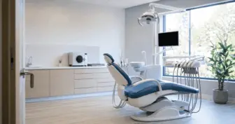 Consultório odontológico recém-montado com cadeira nova e sala de esterilização ao fundo